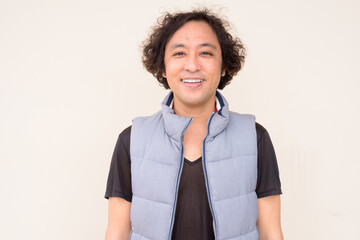 Portrait of happy Japanese man with curly hair smiling © Ranta Images