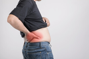 Body pain, hip pain or effect from liver problem : Fat man using his hand and pressing on hip position. Studio shot on grey