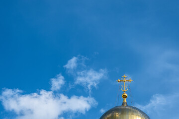 Fototapeta na wymiar Gold cross and the dome of an Orthodox church against the blue sky.
