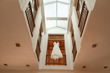 Beautiful white wedding  dress for the bride hanging on the balcony at home