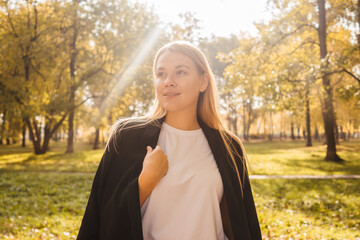 Young woman in blazer on nature. Autumn park, sunny day.