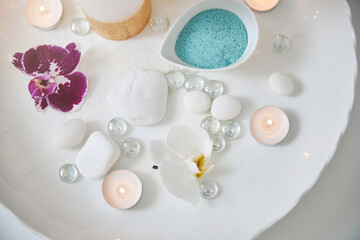 Obraz na płótnie Canvas Flowers and accessories for spa procedure on white plate