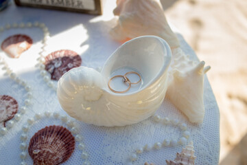 Close up view of wedding rings in the white ceramic shell on the table with wedding decor at the beach wedding ceremony, Punta Cana, Dominican Republic