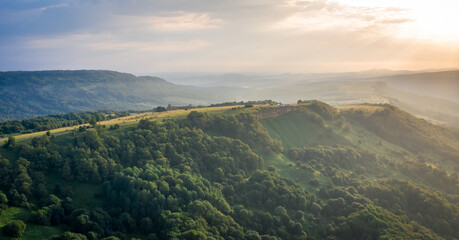 Early morning in the mountains. Morning sun and haze in the valley against the background of mountains. Mountain summer landscape