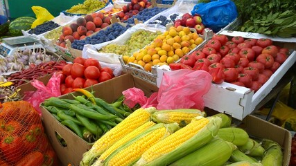 Fresh fruits and vegetables on farmer market. Corn, peppers, tomatoes, plums, peaches, apricots, garlic, grapes on supermarket shelves. Retail industry. Discount. Grocery shopping. Healthy eating.
