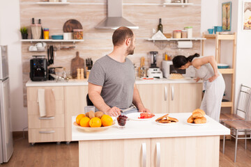 Wife using microwave oven in the morning to prepare the breakfast for her husband. Young housewife at home cooking morning meal, cheerful with affection and love