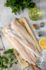 Cod fillet. Raw cod fillet on a chopping Board on a light gray kitchen table. Preparation for...