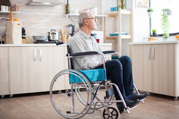 Handicapped senior man in wheelchair feeling lonely looking on the window. Elderly handicapped...