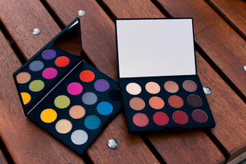 
two makeup palettes on wooden background, closeup