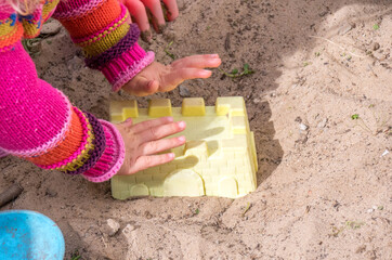 A child plays in the sand with toys on the beach image in horizontal format