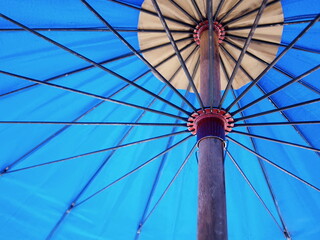 Inside of a large blue umbrella. Spokes and metal buckets support the canvas of the umbrella. Selective focus