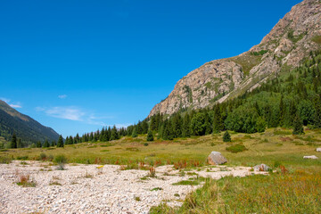 Mountain gorge landscape with cloudy blue sky. Summer nature landscape. Kora river gorge in Kazakhstan, way to Burkhan bulak waterfall. Tourism in Kazakhstan concept.