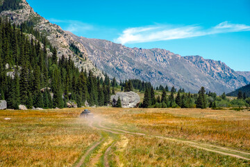 Obraz premium Offroad car is riding on gravel road. Overlanding concept. Kora river gorge in Kazakhstan, way to Burkhan bulak waterfall. Tourism in Kazakhstan concept.