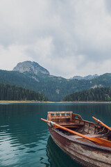 Wooden boat in Black lake at foggy early morning. Durmitor national park, Montenegro