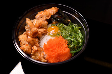 Korean fried chicken dressed with spawn and  Seaweed served in a black bow plastic.