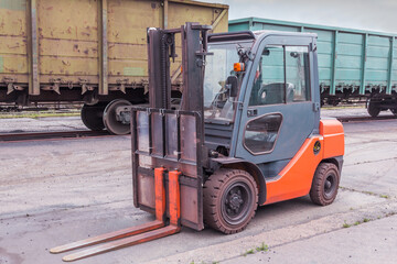 Fototapeta na wymiar Forklift, special equipment on the territory of an open warehouse against the background of freight cars at a railway reloading station.