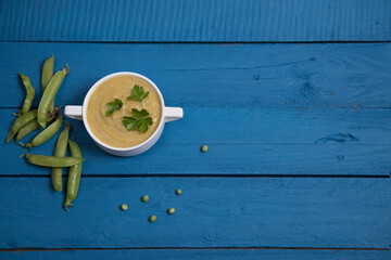 Pea soup in a white Cup on a blue wooden background. Place for a copy space