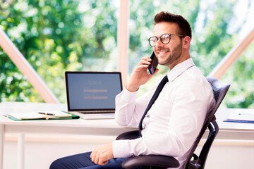 Financial businessman having a phone call while sitting at office desk and working