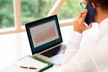 Financial accountant businessman using laptop and mobile phone while working at office desk