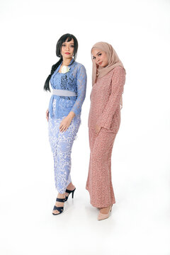 Two South east Asian Malay race ethnic origin woman wearing dress costume kebaya and baju kurung tuding headscarf on white background welcome hand gesture