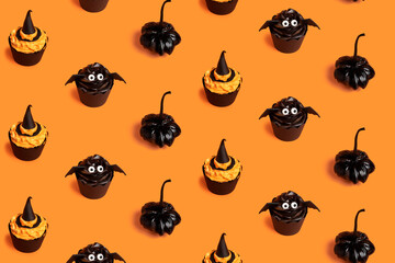 Creative pattern made with black pumpkins, bats, muffins and witch hats on the orange background. Minimal Halloween or Thanksgiving concept. Flat lay.