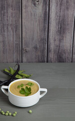 Pea and bean soup in a white Cup on a gray wooden background . Place for a copy space