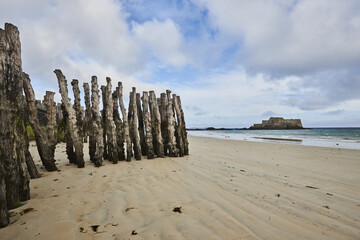 Wooden Poles et Fort National on the beach at low tide in Saint Malo, Brittany, France