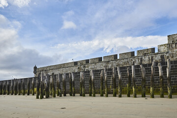 Wooden Poles and rampart  on the beach at low tide in Saint Malo, Brittany, France