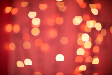 Blurred abstract yellow bokeh Christmas lights on red background.