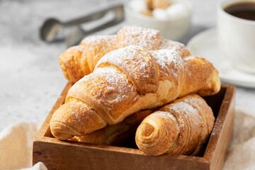 Croissants. Croissants in a wooden box on a light gray background. French breakfast. Croissants closeup