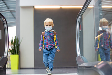 Naklejka na ściany i meble Toddler child, boy, wearing protective medical mask in shopping center during coronavirus pandemic