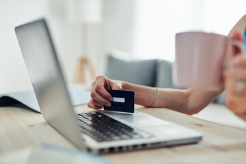 Woman holding credit card and purchasing online with modern laptop.