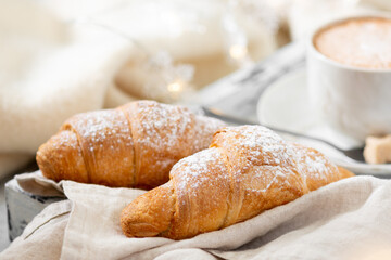 Croissants. Croissants and cappuccino on a wooden tray on a light background. French Breakfast in bed. Croissants close up