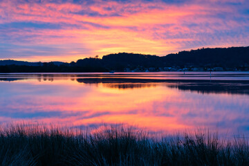 Reflection of Sunrise with soft high cloud over the waterfront