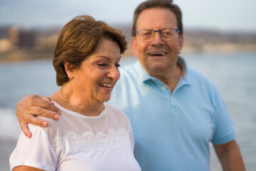 Obraz premium happy retired mature couple walking on the beach - pensioner woman and her husband taking romantic walk together enjoying sweet holidays in lifetime relationship and love