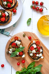 Garlic bruschetta with eggplant, feta, cherry tomatoes, capers. Useful vegetarian appetizer. Italian Cuisine. The top view