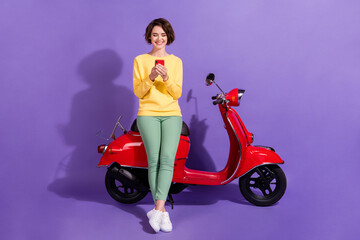 Fototapeta na wymiar Full length body size view nice attractive cheerful girl sitting on bike using device chatting smm app 5g isolated over bright vivid shine vibrant lilac violet purple color background