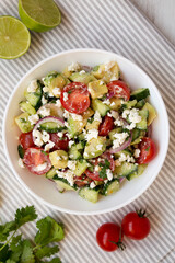 Delicious Avocado Tomato and Cucumber Salad in a bowl on cloth, top view. Flat lay, overhead, from above. Close-up.