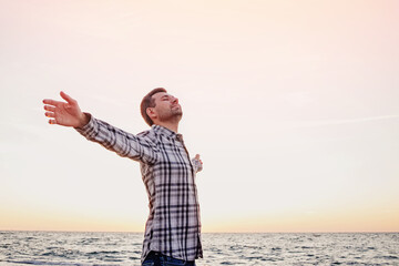 Happy young man standing with arms outstretched