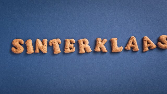 Stop motion animation. Sinterklaas is coming soon, 4K. Dutch holiday St Nicholas day concept with letters traditional cookies, kruidnoten on blue background with copy space. Top view.