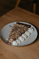 chocolate pancake with bananas, nuts and chocolate sauce. the toning. selective focus. a rolled chocolate pancake is a calorie bomb