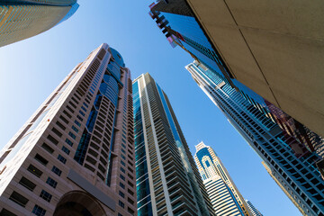 Low angle shot of skyscrapers of financial district of Dubai, UAE at a sunny day. Futuristic low-angle view of the capital of the Emirate of Dubai. A center for international trading of Western Asia.