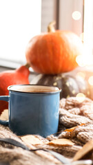 Fototapeta na wymiar Autumn background with dry leaves, blue cup of coffee. Knitted background, pumpkins, October, November. Autumnal atmosphere. Autumn season.