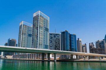 Fototapeta na wymiar Skyscrapers of downtown of Dubai at a sunny day at Dubai Canal, Business Bay, bridge. Futuristic cityscape of the capital of the Emirate of Dubai. International hub of financial services