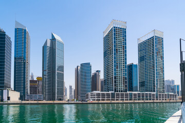 Fototapeta na wymiar Panorama of skyscrapers of downtown of Dubai, UAE at a sunny day at Dubai Canal, Business Bay. Modern cityscape of the capital of the Emirate of Dubai. A center of new tech of Western Asia
