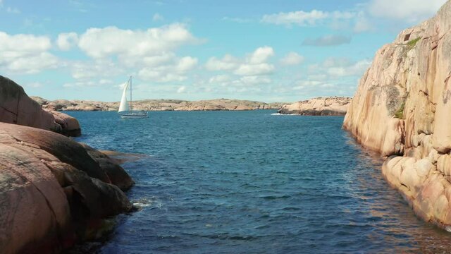 Sailing boat in Sweden between granite stone cliffs and island. Summer boat weather perfect wind for ocean activity. west coast seashore of Sweden close to Gothenburg