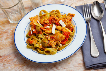 Tasty spinach tagliatelle served with bacon, tomato sauce and cheese, italian cuisine