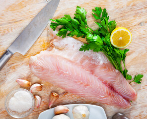 Image of fillet of raw perch fillet before cooking with greens. High quality photo
