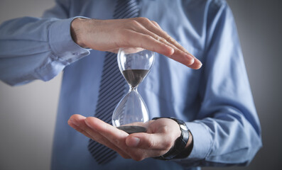 Businessman holding hourglass. Deadline concept