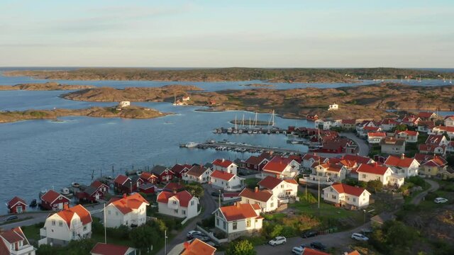 Coastal village in Sweden in gorgeous light. Swedish wooden summer vacation homes by the ocean. Bohuslan island archipelago and harbour. Drone aerial 4k view over dream landscape